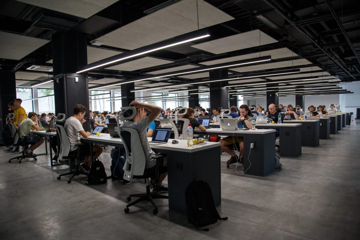 Shot of large scale office with a lot of young workers at communal desks on their computers.