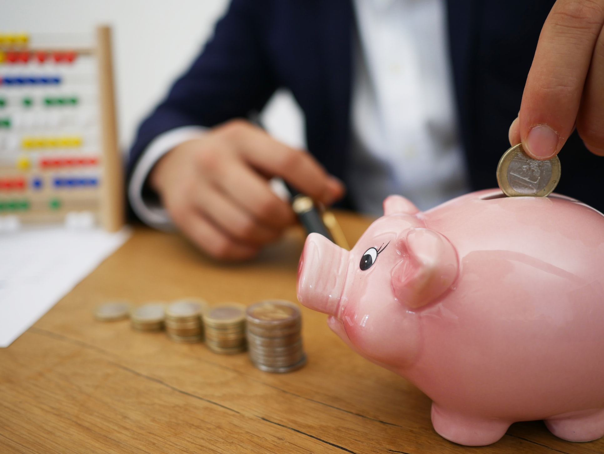 Close up of a man putting change into a piggy bank.