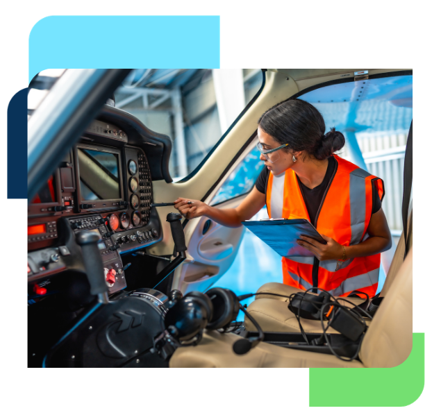 Aviation technician in a high-visibility safety vest inspecting an aircraft cockpit with a tablet during maintenance.