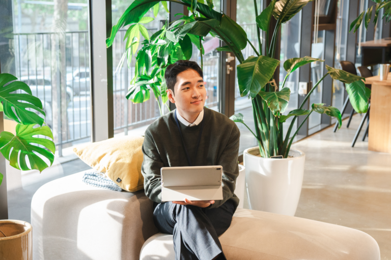Male employee sitting on couch working on laptop.